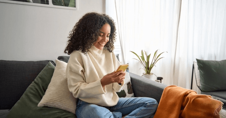 Woman sitting on her couch looking at her phone