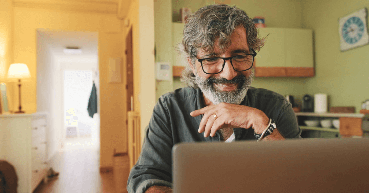 Man with glasses in his home looking at his laptop