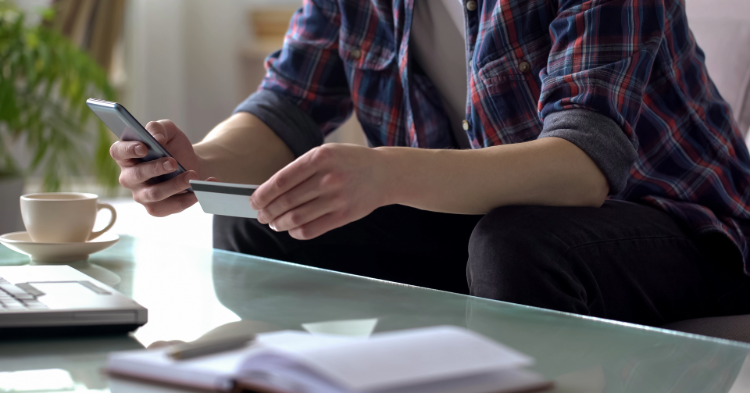 Woman at a laptop holding a paper and making a budget