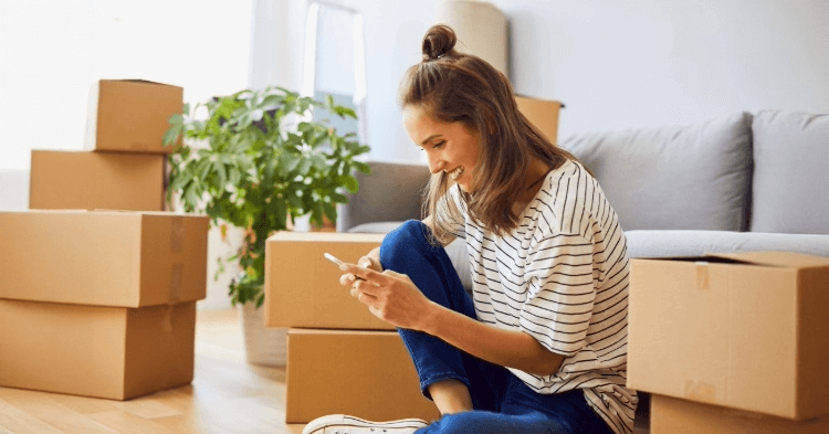 Woman on her phone with moving boxes all around