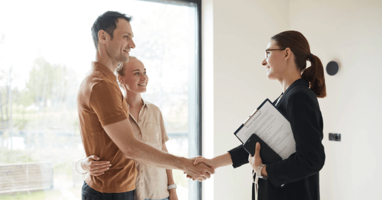 A couple shaking hands with a real estate agent.