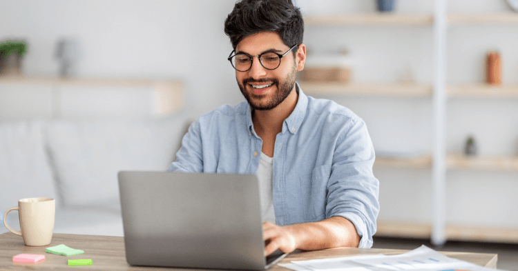 Man wearing glasses reviewing something on a laptop