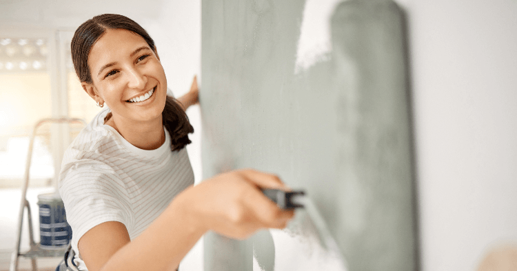 Smiling woman painting a wall gray.