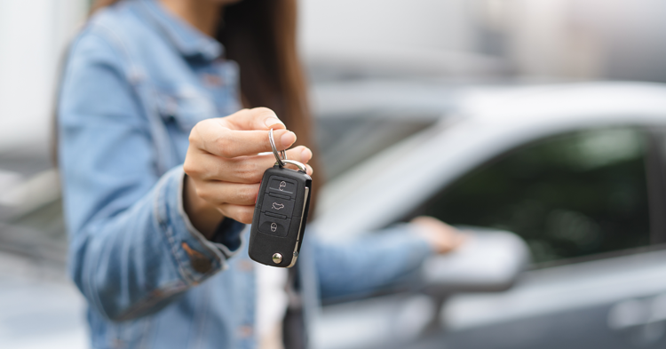 Woman holding car key out toward the camera